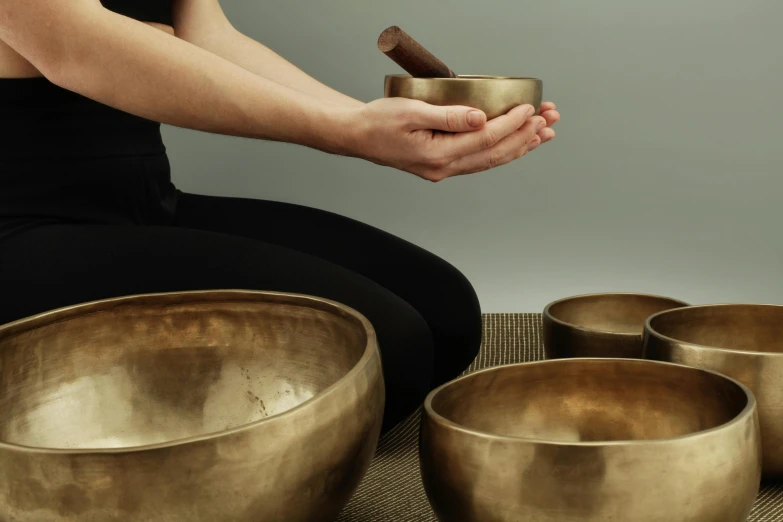 a woman sitting on a mat holding a bowl, inspired by Gong Kai, trending on pexels, brass instruments, hands pressed together in bow, asset on grey background, made in bronze