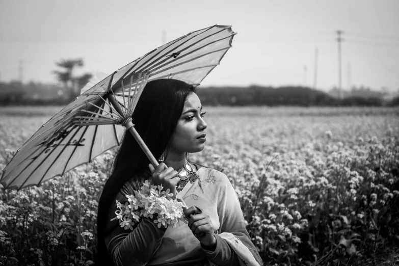 a woman holding an umbrella in a field of flowers, a black and white photo, by Sunil Das, unsplash, traditional portrait, assamese aesthetic, ☁🌪🌙👩🏾, icon