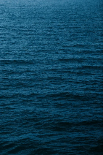 a boat floating on top of a large body of water, an album cover, trending on unsplash, minimalism, prussian blue, 2 5 6 x 2 5 6 pixels, rough waves, deep dark sea