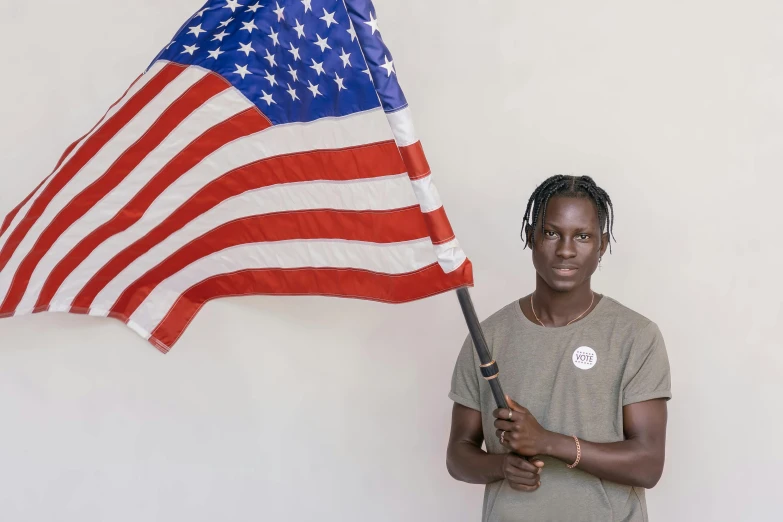 a woman holding an american flag in front of a white wall, trending on unsplash, american realism, black teenage boy, adut akech, ignant, a photo of a man
