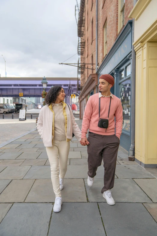 a man and a woman walking down a sidewalk, pastel clothing, london streets in background, non-binary, hispanic