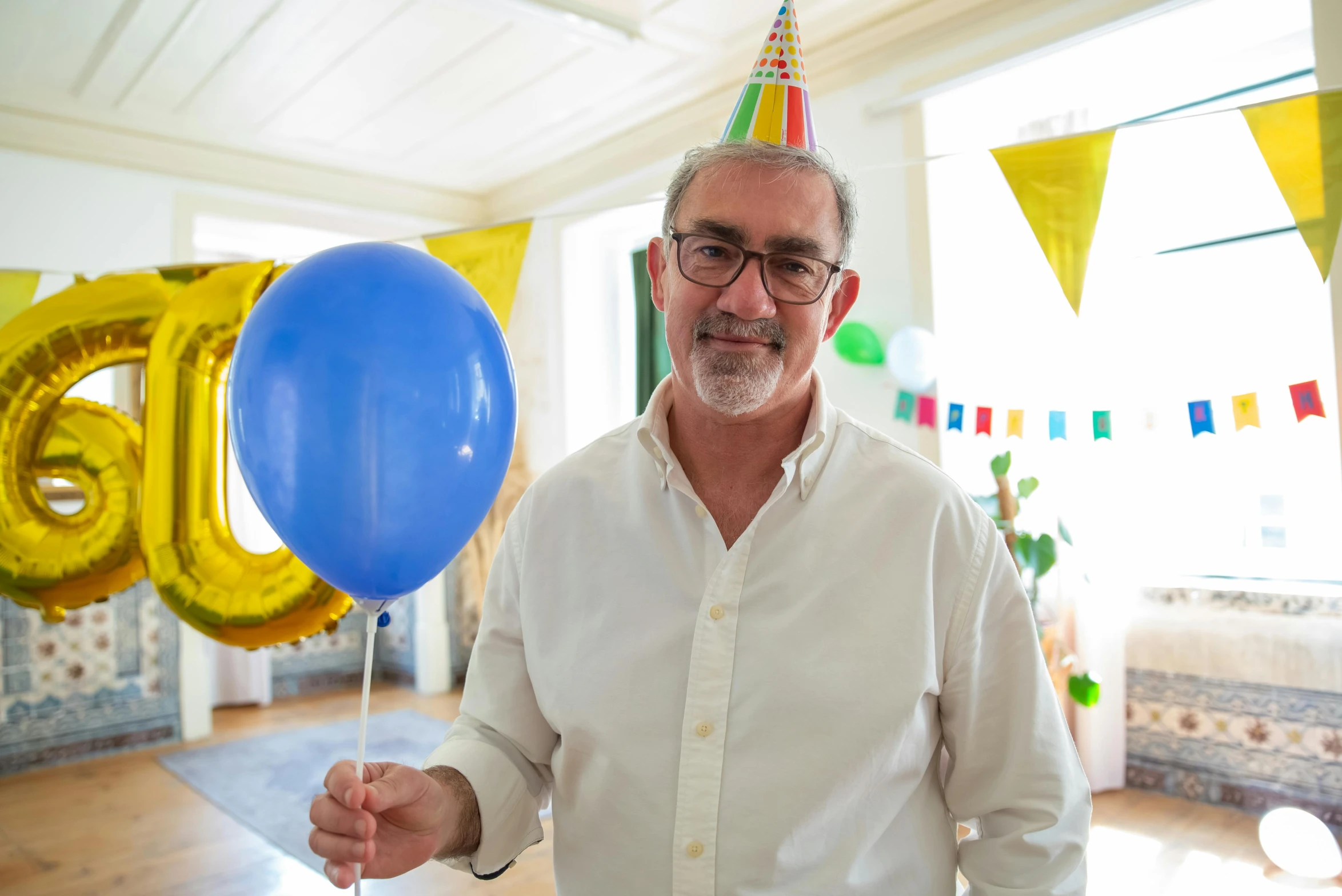 a man in a party hat holding a blue balloon, portrait image, renzo piano, matt howarth, profile image