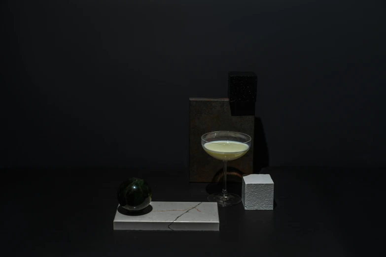 a glass filled with liquid sitting on top of a table, a still life, inspired by Carlo Martini, suprematism, obsidian globe, an elegant green, white concrete, the sour