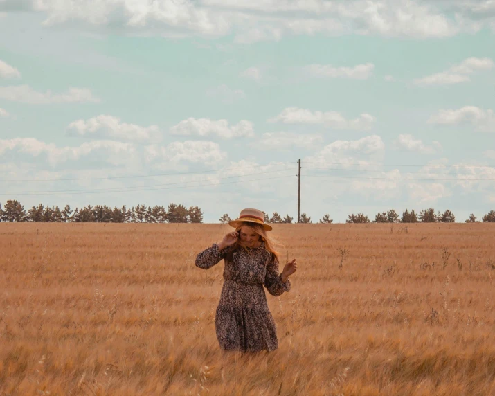 a woman standing in a field with a hat on, pexels contest winner, southern slav features, running freely, an australian summer landscape, brown