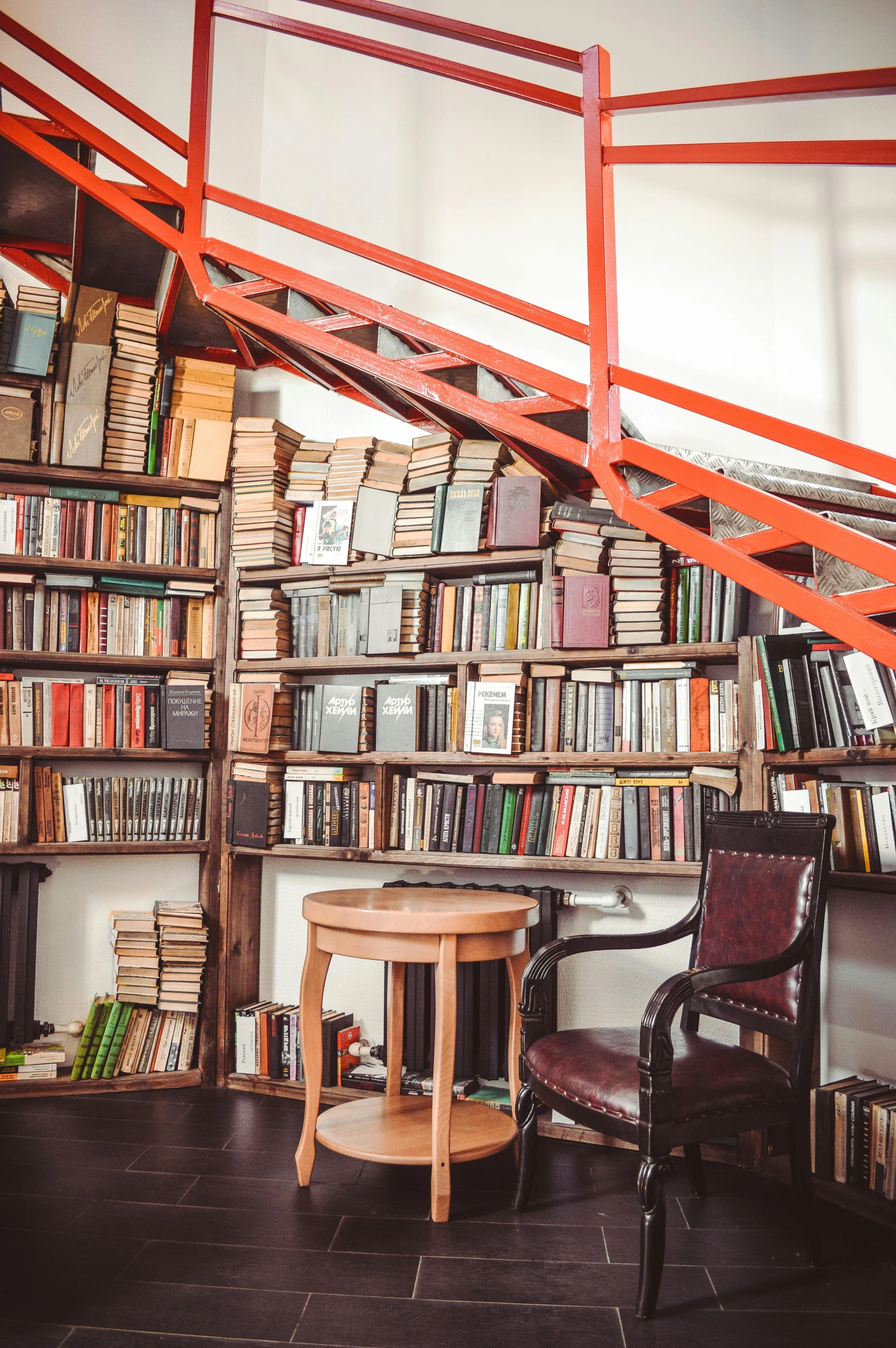 a chair sitting in front of a bookshelf filled with lots of books, spiral stairs, overhead, an escape room in a small, ignant