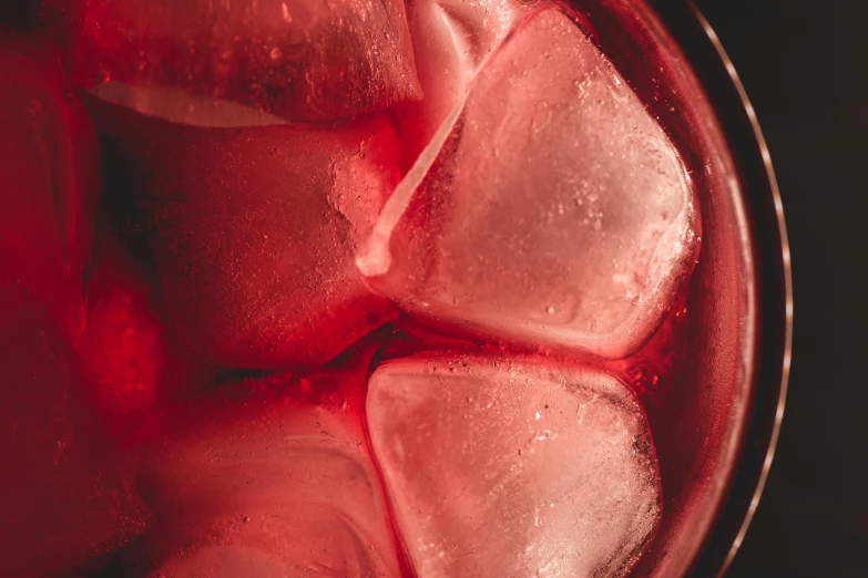 a glass filled with ice cubes on top of a table, strong red hue, thumbnail, thighs close up, fan favorite