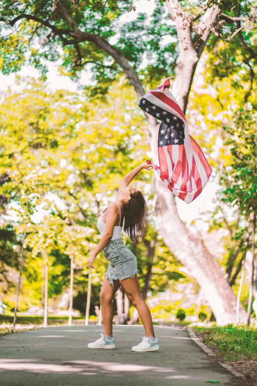 a woman holding an american flag in a park, leaping from babaob tree, instagram post, flags, lifestyle