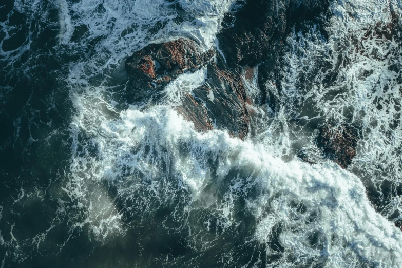 a large body of water next to a rocky shore, an album cover, by Adam Marczyński, pexels contest winner, turbulent waves, satellite view, quixel textures, overflowing energy