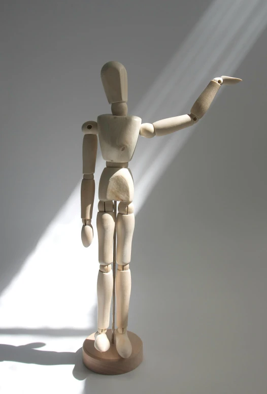 a wooden mannequin standing in front of a white wall, by David Simpson, pexels, articulated joints, action figurine toy, light ray, taken in the late 2000s
