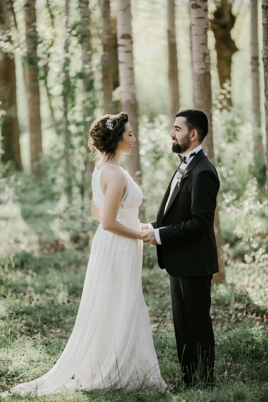 a bride and groom standing in the woods, looking at each other mindlessly, with a small forest, featured, may)