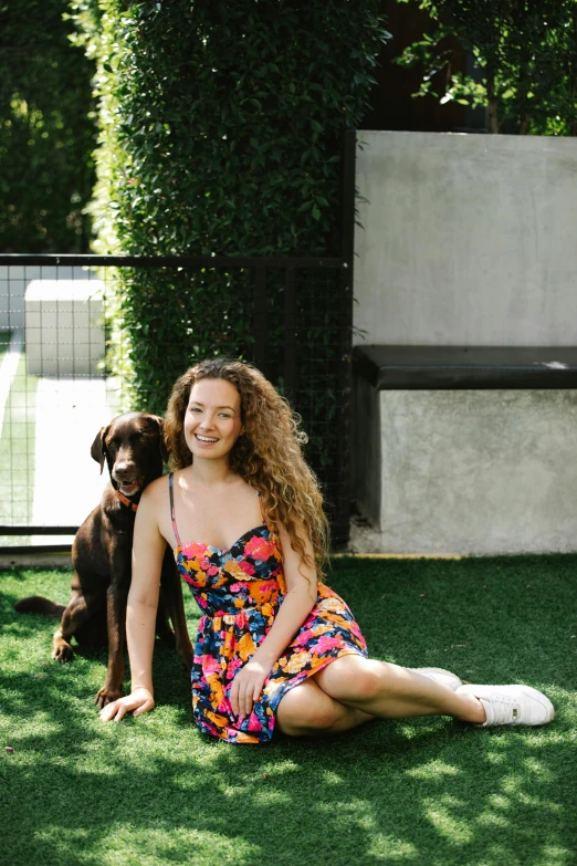 a woman sitting on the grass with a dog, brown curly hair, kailee mandel, 2 5 yo, single subject