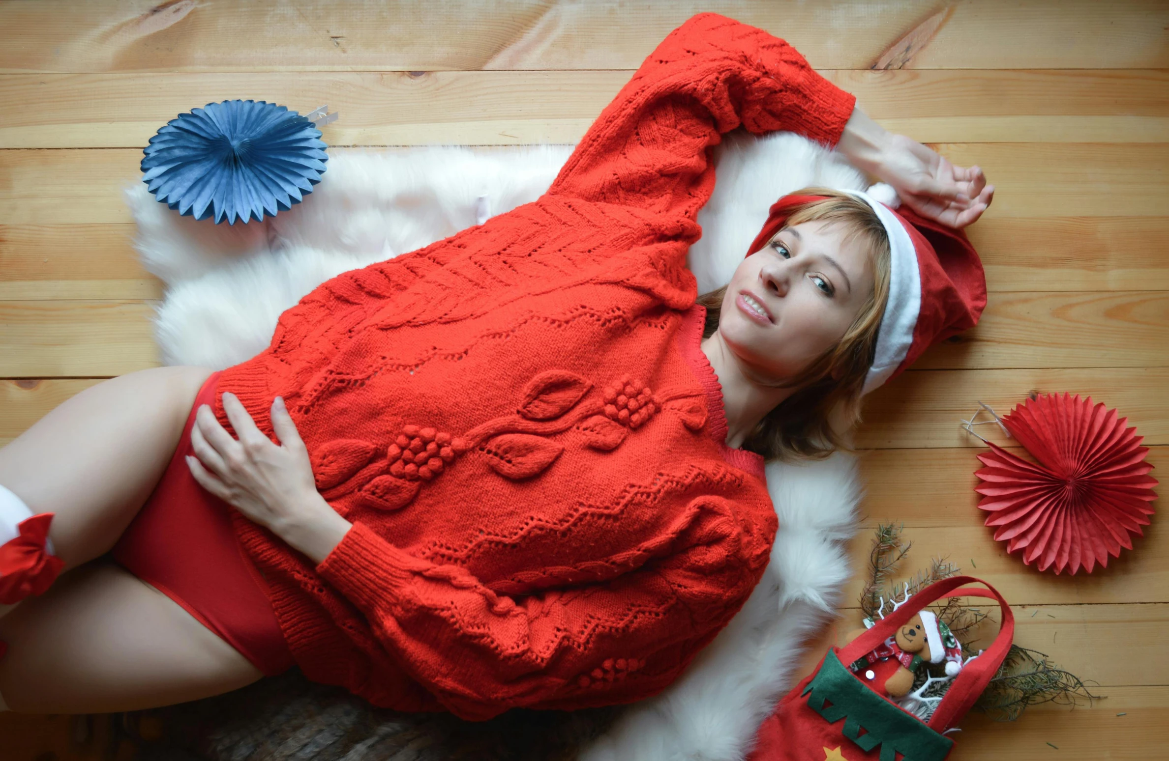 a beautiful woman laying on top of a wooden floor, by Julia Pishtar, pexels contest winner, wearing festive clothing, wearing an oversized sweater, wearing red, in a medium full shot