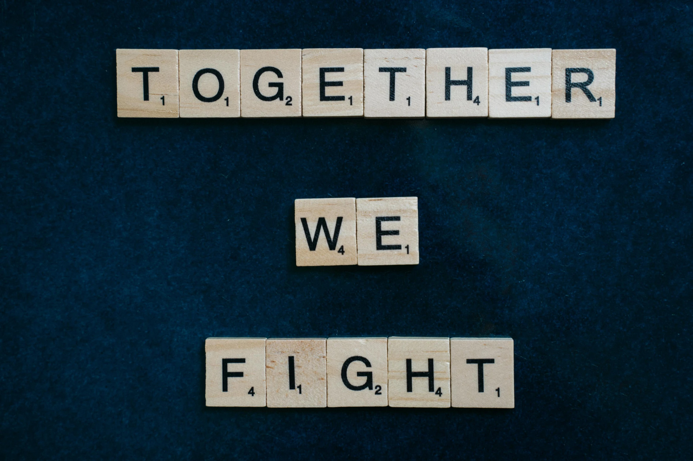 scrabbles spelling together we fight on a blue background, a picture, by Niko Henrichon, pexels contest winner, background image, taken with sony alpha 9, tamara de lepika, fighter