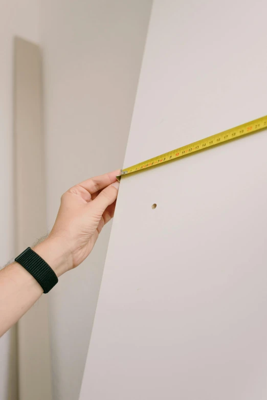 a person measuring a wall with a tape, unsplash, plain background, low quality photo, measurements, 1 : 1 aspect ratio