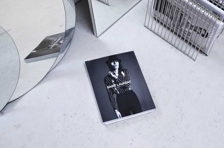 a magazine sitting on top of a table next to a mirror, an album cover, inspired by Carles Delclaux Is, unsplash, photorealism, polaroid fashion photography, b&w hasselblatt, with bangs, lomography lady grey