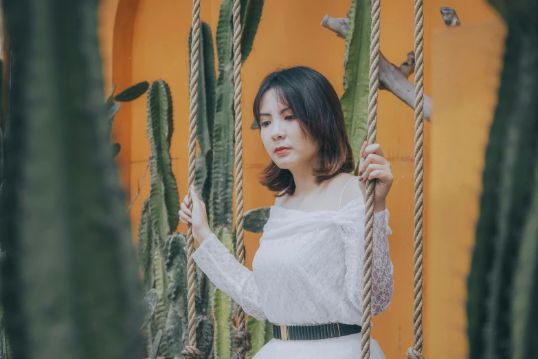 a woman in a white dress standing next to a cactus, inspired by Elsa Bleda, pexels contest winner, asian girl, swings, avatar image, background image