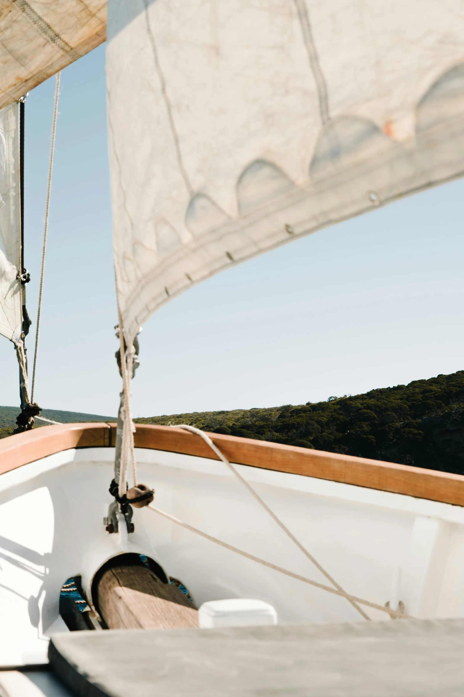 a man sitting on the bow of a sailboat, trending on unsplash, arts and crafts movement, square jaw-line, hills and ocean, manly, canopy