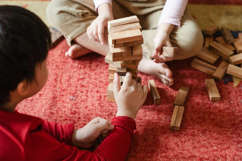 two children playing with wooden blocks on the floor, by Julia Pishtar, pexels contest winner, bruegels the tower of babel, closeup of arms, traditional japanese, with furniture overturned