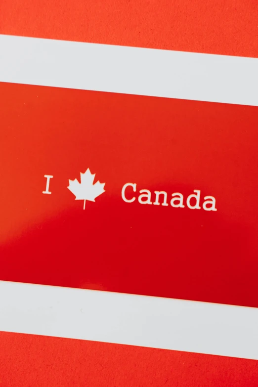 i love canada sticker on a red background, by Julia Pishtar, high angle close up shot, focus on card, on grey background, wide image