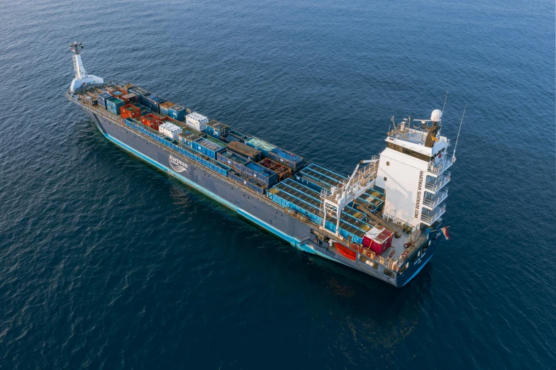 a large cargo ship in the middle of the ocean, brown and cyan blue color scheme, argos, looks directly at camera, slide show