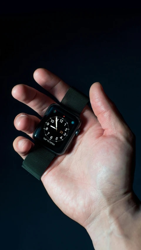 a person holding an apple watch in their hand, by Adam Marczyński, pexels, hypermodernism, black on black, square, small in size, robotics