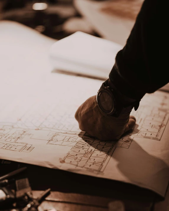 a close up of a person's hand on a piece of paper, a detailed drawing, pexels contest winner, constructivism, building plans, handsome, manly design, lgbtq