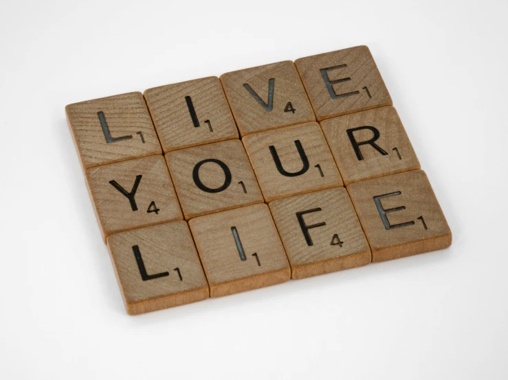 a scrabble with the words live your life written on it, by Sylvia Wishart, official product photo, squares, tan, wooden
