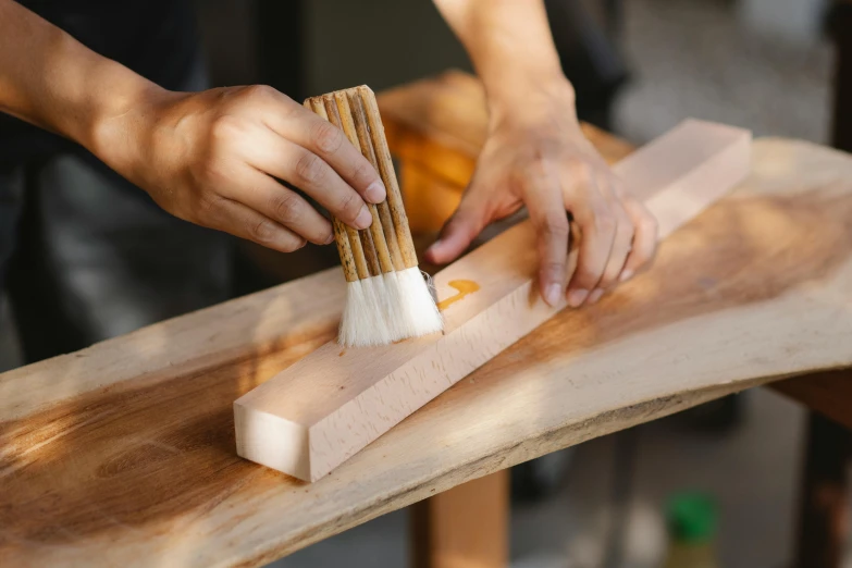 a person using a brush to paint a piece of wood, inspired by Kanō Shōsenin, pexels contest winner, avatar image, rectangle, soap carving, manuka