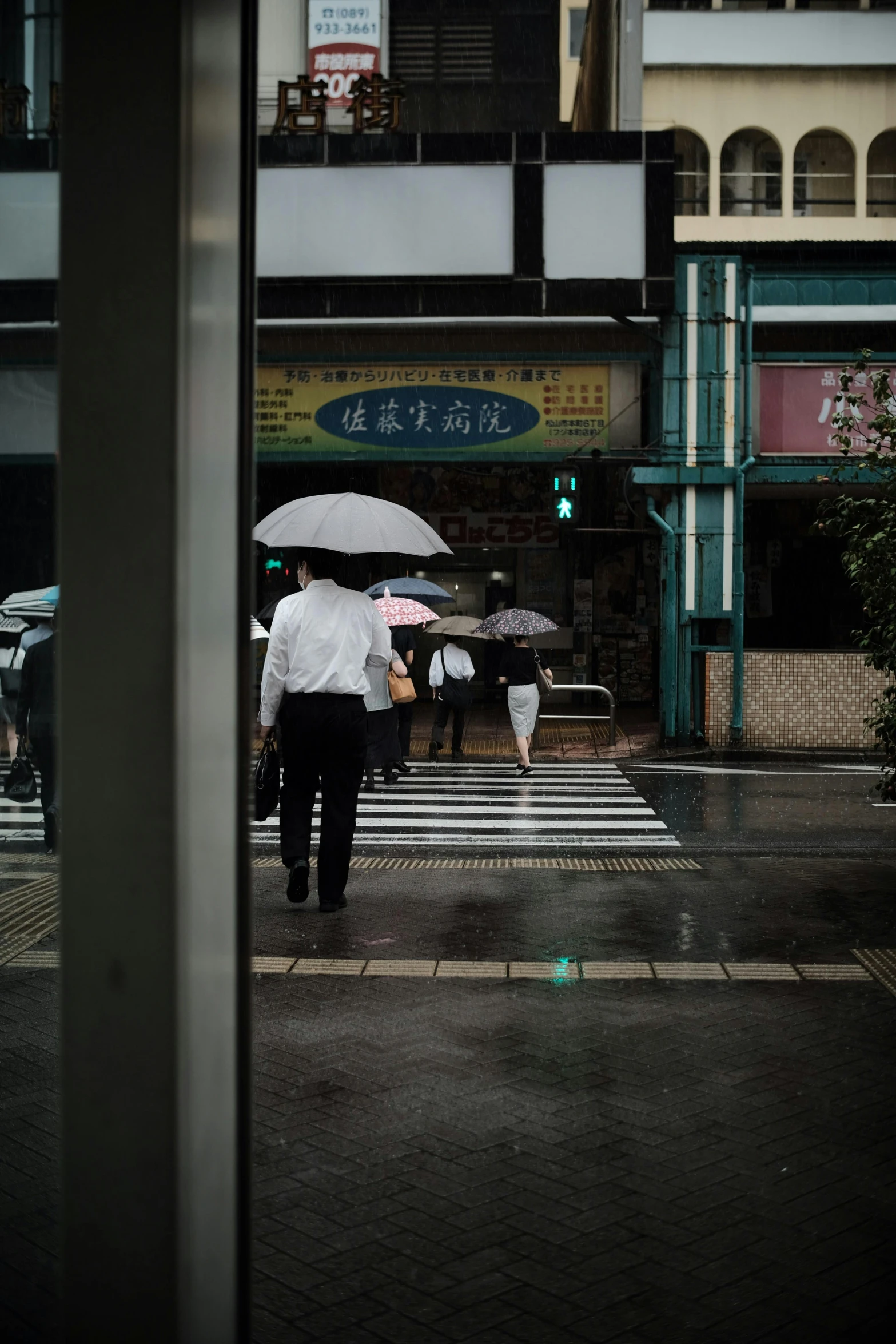 a group of people walking across a street holding umbrellas, shin hanga, ominous photo, street corner, rule of thirds, color photograph