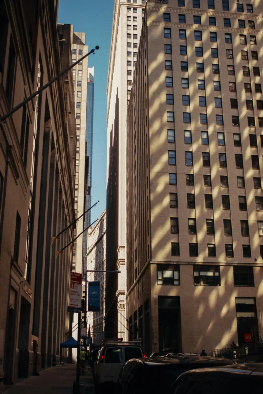 a city street filled with lots of tall buildings, inspired by Vivian Maier, unsplash contest winner, afternoon sunlight, 3 5 mm color photography, location [ chicago ( alley ) ], tall buildings