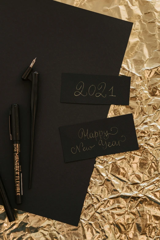 a couple of pens sitting on top of a piece of paper, black and gold palette, new years eve, promo image, chalk