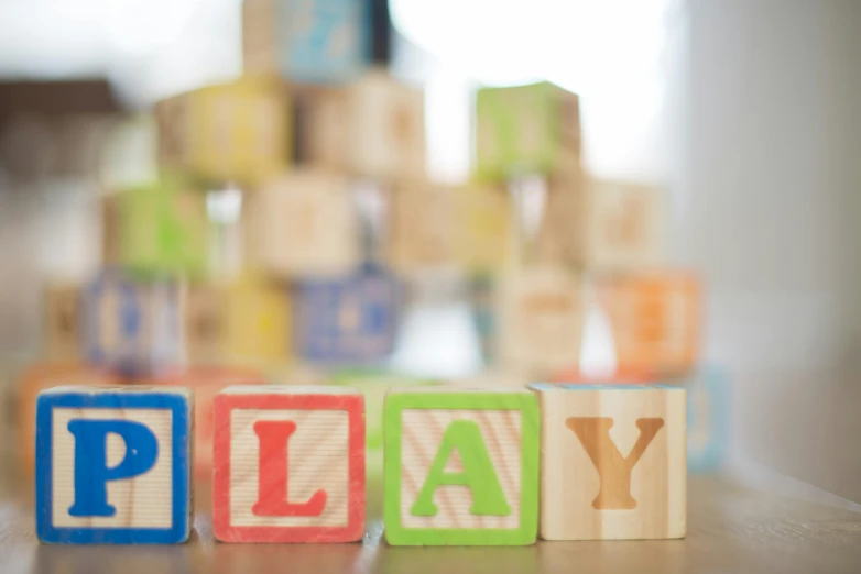 wooden blocks spelling play on a table, pexels contest winner, fan favorite, blurred, healthcare, softplay