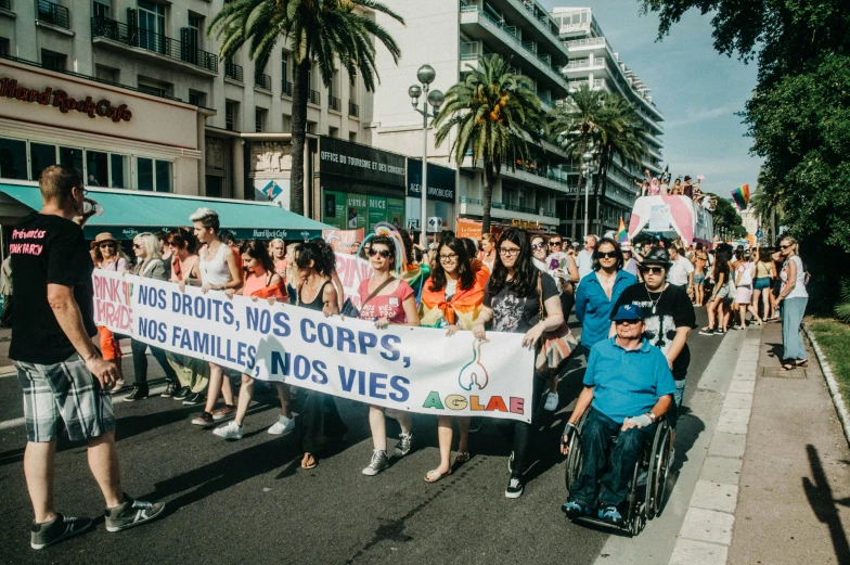 a group of people walking down a street holding a banner, by Julia Pishtar, pexels, les automatistes, accessible for the disabled, cannes, pride parade, protesters holding placards