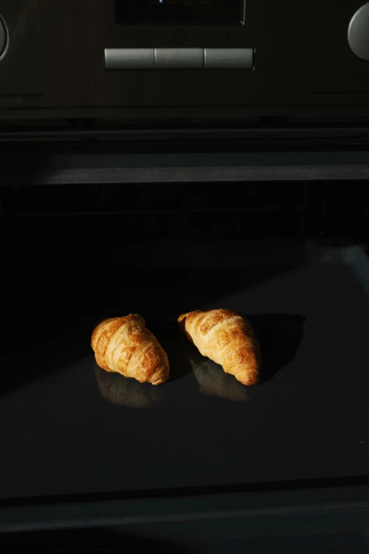 two croissants are baking in an oven, inspired by Gillis Rombouts, hyperrealism, uv, soft light - n 9, 1 4 8 0 s, minimalissimo