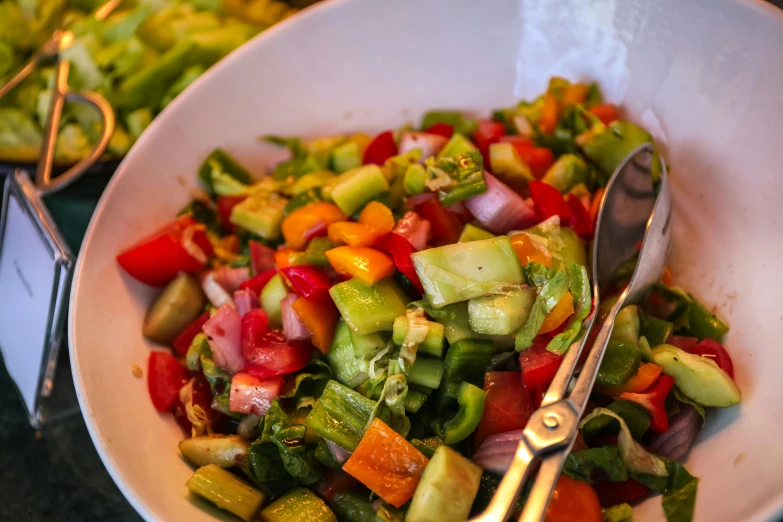 a close up of a bowl of food with a spoon, cutting a salad, profile image