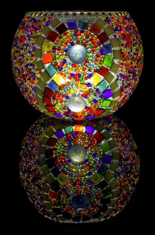 a lit candle sitting on top of a reflective surface, a mosaic, inspired by Ahmed Yacoubi, flickr, cloisonnism, glass spheres, closeup!!!!!!, made of multicolored crystals, centerpiece symmetry