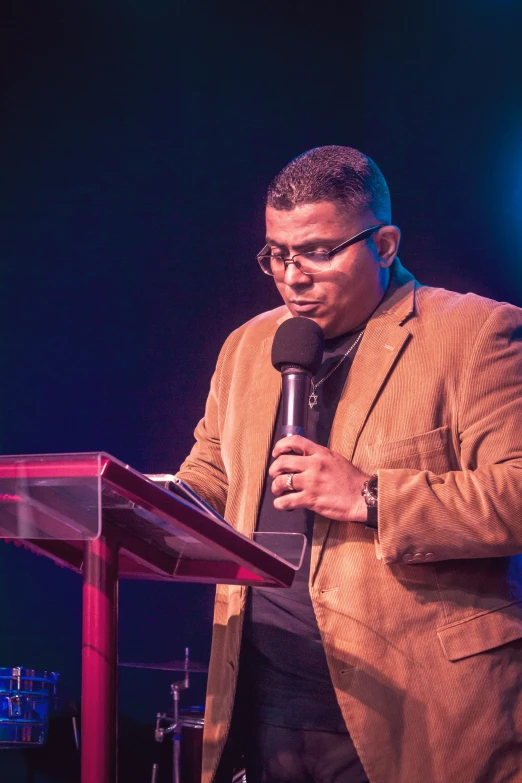 a man standing at a podium with a microphone, ronaldo nazario fenomeno, listening to godly music, man with glasses, (night)