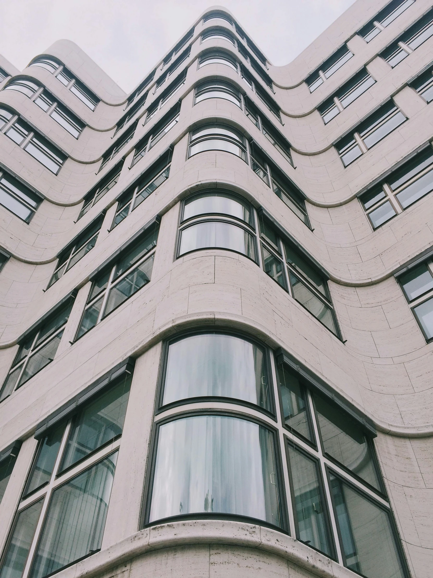 a tall white building with lots of windows, unsplash contest winner, curved body, trending on vsco, window ( city ), gray concrete