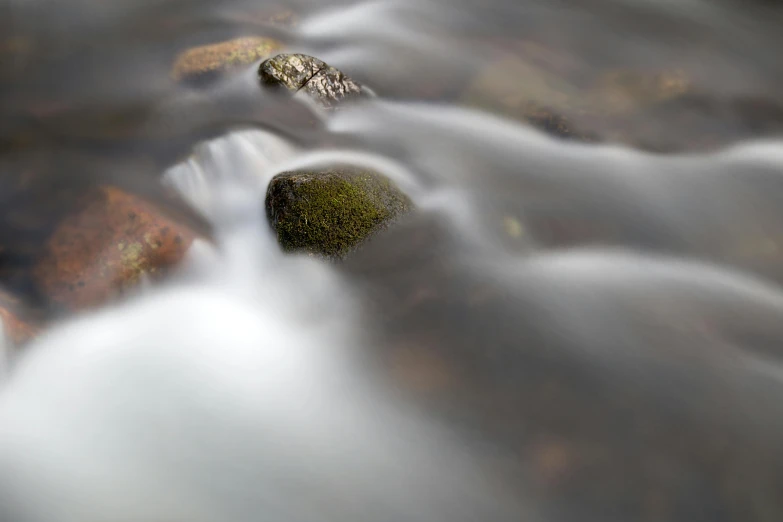 the water is flowing over the rocks in the stream, by David Simpson, unsplash, tonalism, soft focus blur, grey, 4 k smooth, chocolate river