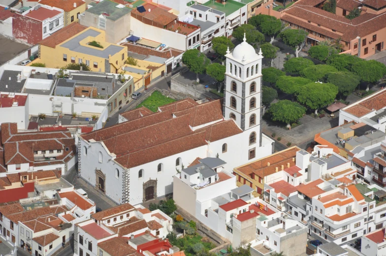 an aerial view of a city with a clock tower, inspired by Pedro Álvarez Castelló, white buildings with red roofs, church cathedral, múseca illil, brown