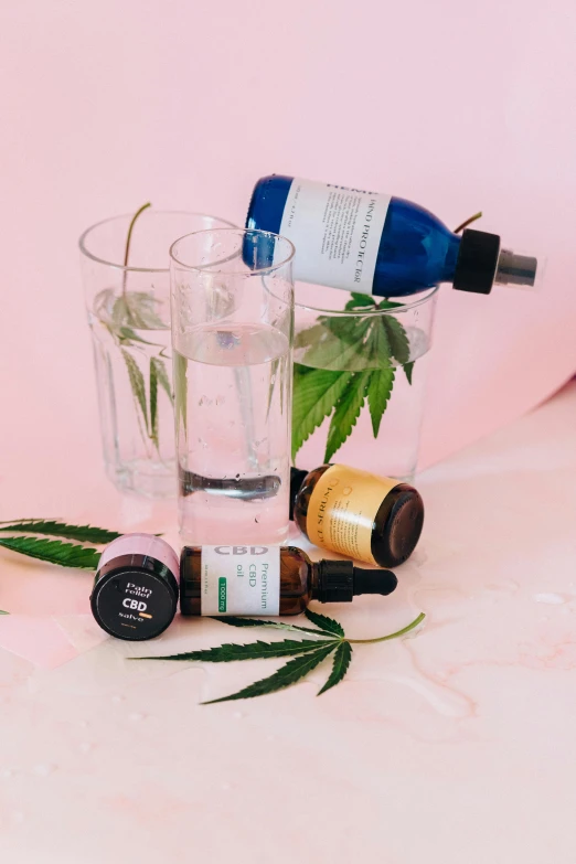 a bottle of water sitting on top of a table next to a glass of water, 4 cannabis pots, skincare, detailed product image, cosmopolitan