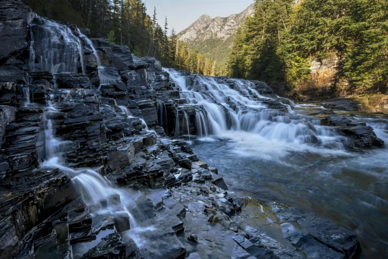 a waterfall in the middle of a forest, by Jim Nelson, unsplash contest winner, hurufiyya, glacier national park, shiny layered geological strata, promo image, several waterfalls