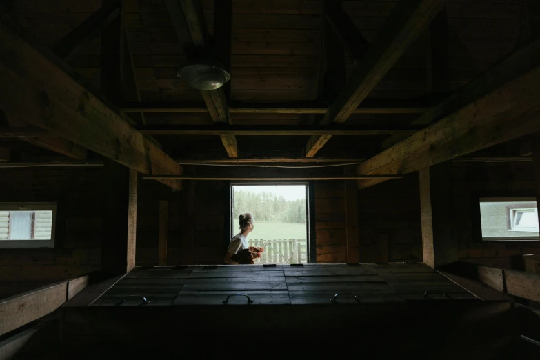 a woman standing in a barn looking out a window, inspired by Gregory Crewdson, unsplash contest winner, light and space, wide high angle view, sitting on top a table, looking upwards, multiple stories