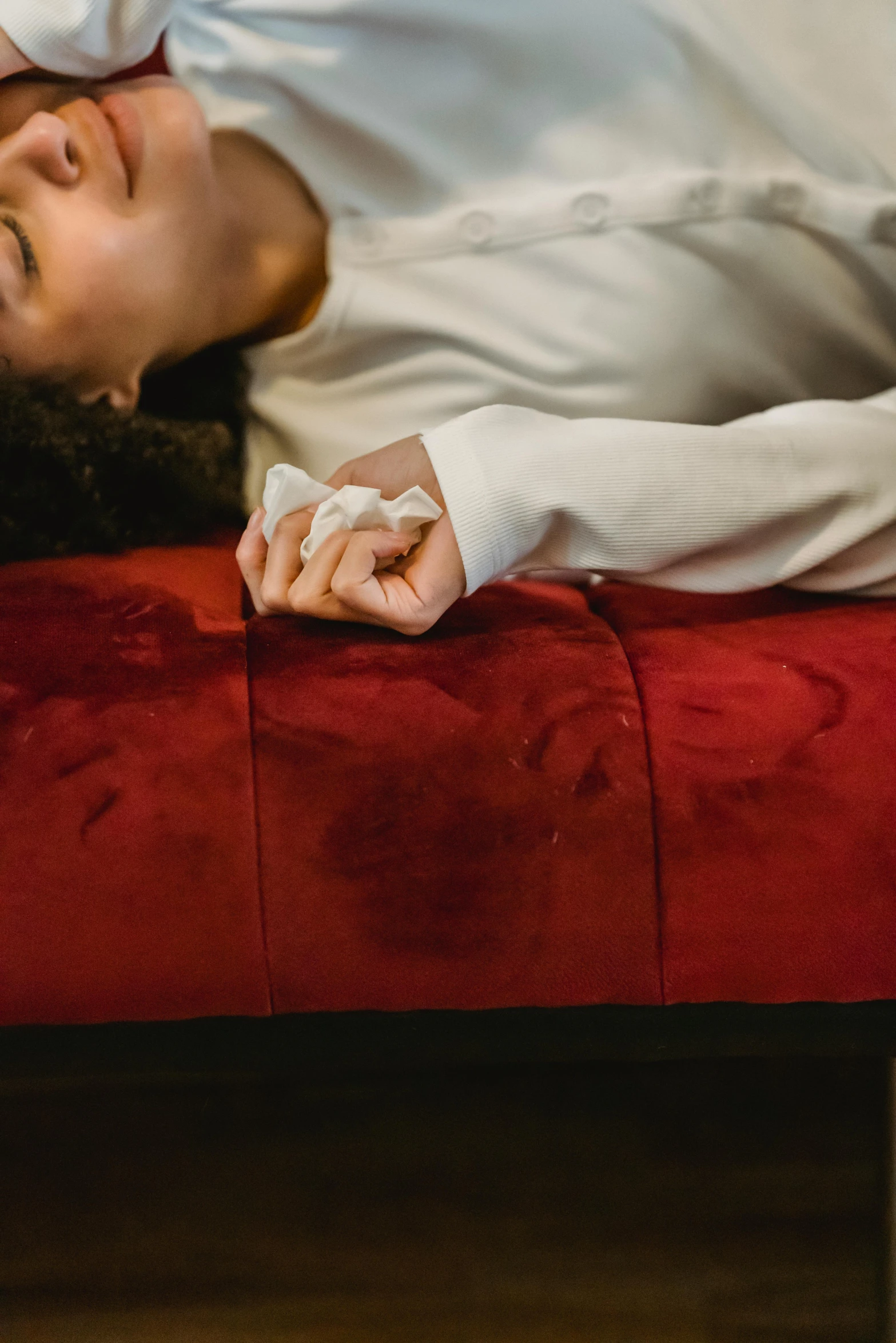 a woman laying on top of a red couch, by Elsa Bleda, pexels, blood stains on shirt, coughing, close up angle, foam