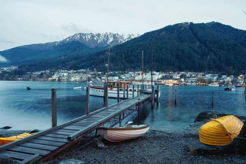 a dock with boats and mountains in the background, by James Ardern Grant, unsplash contest winner, hurufiyya, cottage town, dingy gym, victorian harbour night, 90s photo