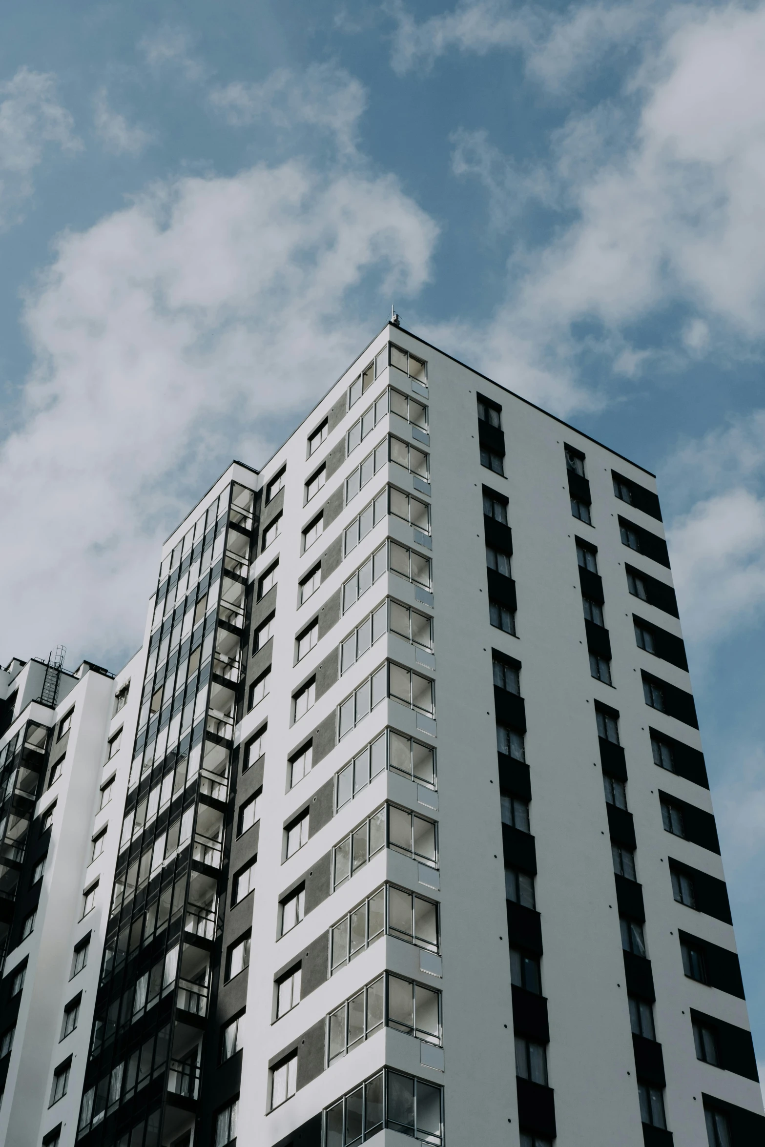 a tall white building with lots of windows, a cartoon, unsplash, grey clouds, low quality photo, city apartment, video