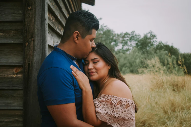 a couple standing next to each other in a field, pexels contest winner, hispanic, background image, stacked image, embraced