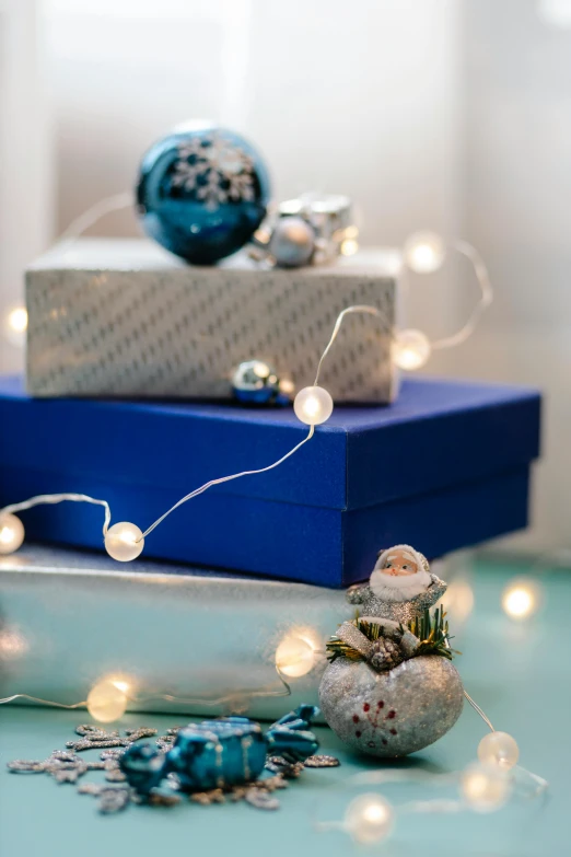 a stack of christmas presents sitting on top of a table, inspired by Ernest William Christmas, happening, blue accent lighting, emitting light ornaments, detail shot, full product shot