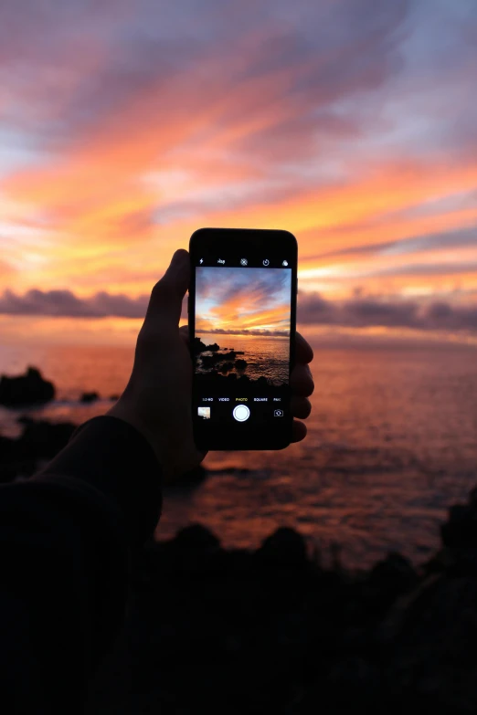 a person taking a picture of a sunset, a picture, uploaded