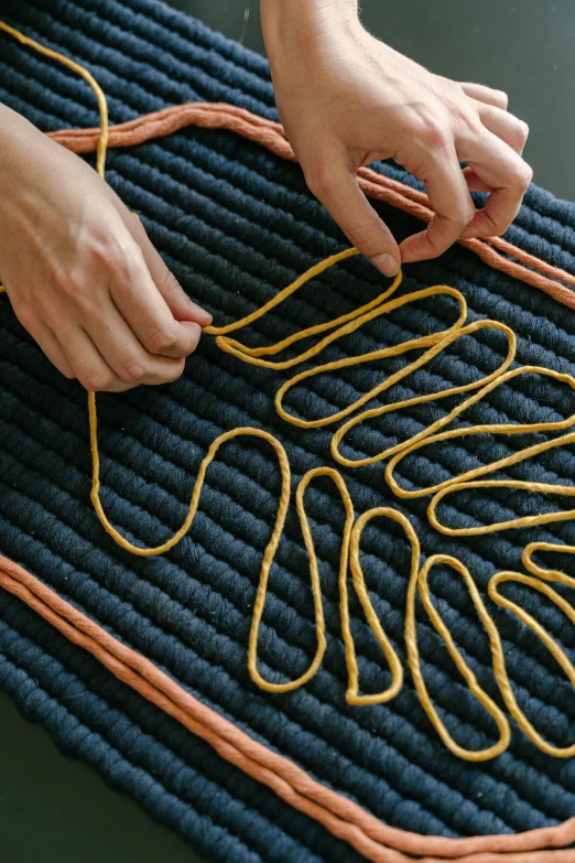 a person tying a rope on top of a rug, detailed product image, ocher details, carbon fibers, pitch bending